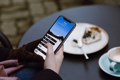 カフェでケーキを食べながらスマートフォンを操作する女性